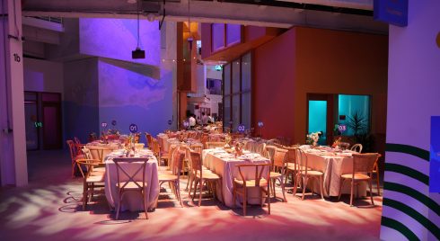Meta Leadership Day 2025 dining area with long rectangular tables, wooden chairs, white linens, and ambient purple pink lighting