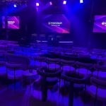 Polychain Investor Day 2025 event stage with branded screens and theater seating with purple and blue lighting