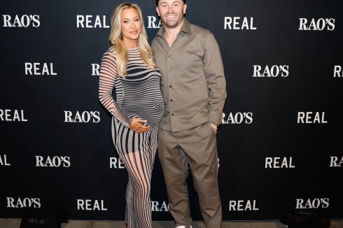 Couple posing on red carpet at Rao's Crucial Catch step and repeat banner with REAL and Rao's branding