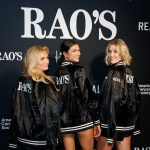 Three guests in Rao's branded satin jackets posing at Crucial Catch to Intercept Cancer step and repeat banner